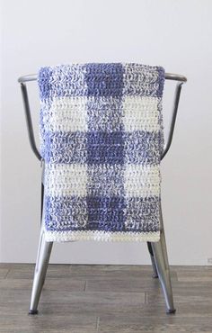 a blue and white blanket sitting on top of a metal chair with the words crochet