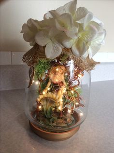 a glass vase filled with white flowers and fairy lights