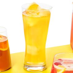 three glasses filled with different types of drinks next to each other on a yellow table