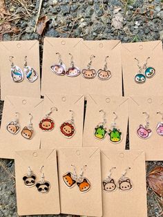 six pairs of earrings with animal faces on them sitting in front of some brown paper