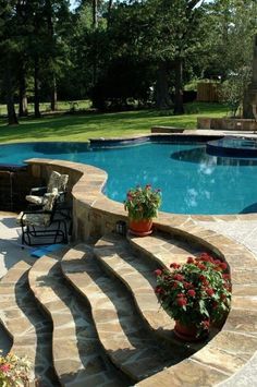 a swimming pool with steps leading up to it and potted plants in the foreground