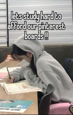 a person sitting at a desk with a book and pen in their hand, writing on paper