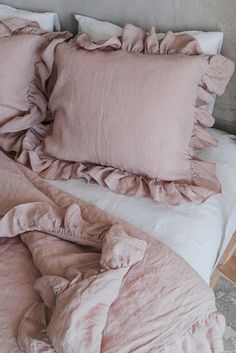 an unmade bed with pink sheets and ruffles on the pillowcase is shown