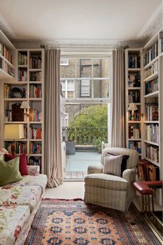 a living room filled with lots of furniture and bookshelves next to a window