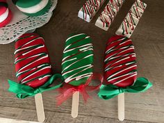 three candy lollipops on sticks decorated with green and red striped icing