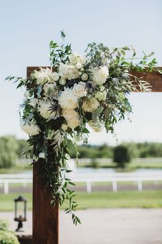 a bouquet of white flowers hanging from a wooden cross