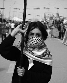 a woman with a scarf on her face holding a pole