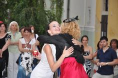 two women hugging each other in front of a group of people and one woman is holding an apple