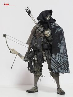 an action figure holding a bow and arrow in his hands, wearing a hooded outfit