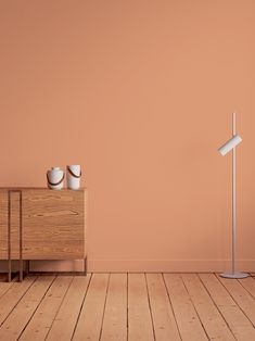 an empty room with two lamps and a dresser in the foreground, against a peach colored wall