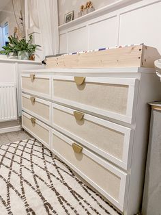 a white dresser sitting on top of a rug next to a window