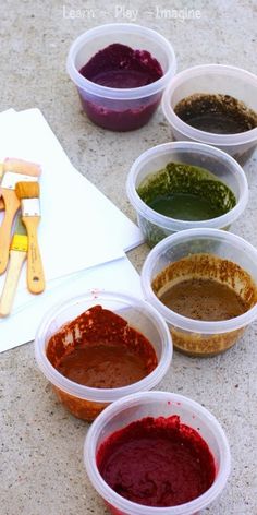 six different colored sauces in plastic containers on a table with utensils and paper towel