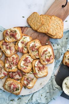 some crackers are sitting on a plate with cheese and other food items around them