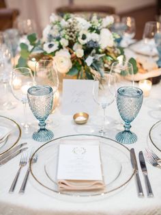 the table is set with silverware and white flowers