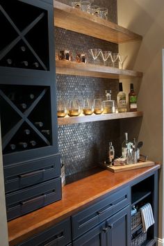 a kitchen counter with wine glasses on it and shelves filled with bottles in the background