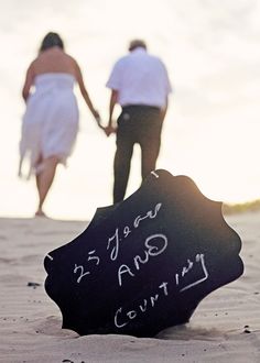 two people walking in the sand with a sign that says love and life written on it