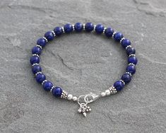 All natural vibrant blue Lapis Lazuli beads are paired with Bali style Turkish sterling silver accents and finished with a secure sterling silver lobster clasp in this bracelet. I also added a few coordinating sterling silver charms for an extra accent. Perfect to wear by itself or with other bracelets for a stacked look. Sterling silver is .925 pure silver. Bali silver is .925 pure silver. Turkish silver is .925 pure silver. See more Lapis Lazuli jewelry here: https://www.etsy.com/shop/LindseyS Spiritual Beaded Bracelets With Sterling Silver Clasp, Blue Beaded Bracelets With Sterling Silver Clasp, Blue Sterling Silver Bracelet With Round Beads As Gift, Blue Beaded Bracelets With Sterling Silver Gemstone Beads, Adjustable Blue Beaded Bracelet With Sterling Silver Clasp, Lapis Lazuli Jewelry, Bali Style, Bali Silver, Lapis Lazuli Beads