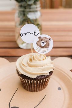 there is a cupcake on the plate with a teddy bear topper in it