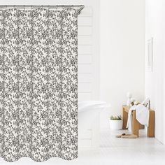 a white bath tub sitting next to a shower curtain with black and white designs on it