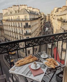 two plates of bread and coffee sit on a balcony overlooking the street in paris, france