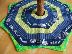 a tree stump sitting on top of a blue and green table cloth covered with seattle football logos