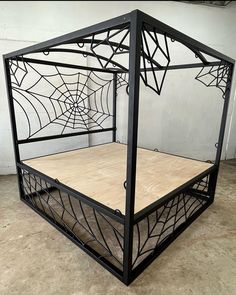 a bed made out of metal and wood with a spider web on it