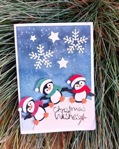 a christmas card with penguins and snowflakes hanging from a pine tree in the background