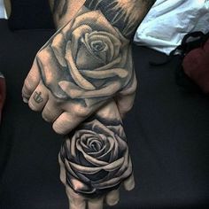 a person with tattoos on their hands holding a rose and cross tattooed on his hand