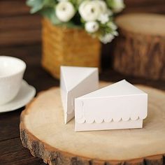 a small white box sitting on top of a wooden table next to a cup and saucer