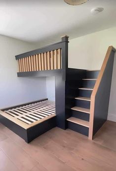 a black bunk bed with stairs in the corner and wooden steps leading up to it