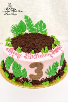 a pink and green birthday cake with leaves on it