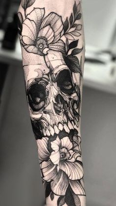 a skull with flowers on it's arm and the lower half of its arm