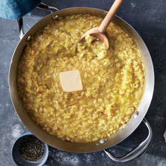 a large pot filled with yellow food next to two spoons and some other items