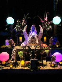 the statue is surrounded by candles and other decorative items in front of an array of lights