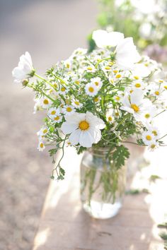 a glass vase filled with white and yellow flowers