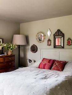 a white bed sitting in a bedroom next to two mirrors on the wall above it