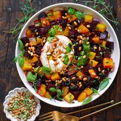 a white bowl filled with beets, carrots and chickpeas on top of a wooden table