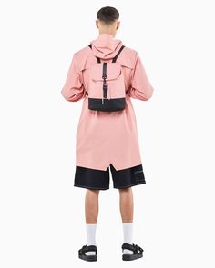 a man in a pink jacket and black shorts is looking at the back of his outfit