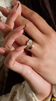 a woman's hand with two rings on her fingers and one ring in the other