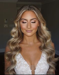 a woman with long blonde hair wearing a wedding dress and makeup is looking at the camera