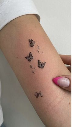 a woman's arm with butterflies and the letter m tattooed on her left arm