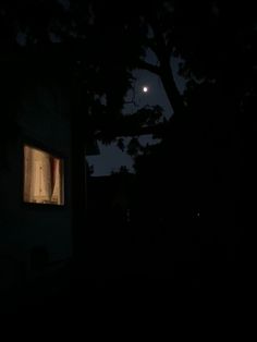 the moon is shining brightly in the dark night sky over a house with open windows