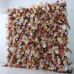 an art piece made out of flowers on the wall in front of a white wall