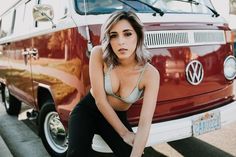 a woman is posing in front of a vw van with her hands on the ground