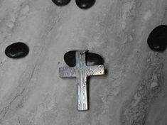 Introducing our exquisite Damasteel cross pendant (Large) - a one-of-a-kind piece of jewelry handcrafted with impeccable attention to detail. Made from the finest quality Damasteel, this unique pendant showcases a mesmerizing pattern created through a complex process of layering and forging multiple types of stainless steel. The sleek and simple design allows the beauty of the Damasteel to be the focal point, making it a versatile accessory that can be dressed up or down.  The nature of the Damasteel material from which this pendant is crafted ensures a unique and one-of-a-kind piece to treasure for years to come. Invest in luxury and craftsmanship with our Damasteel cross pendant - a true symbol of quality and style. We offer several hanging options with all our pendants.  The options we Artisan Engraved Cross Pendant Jewelry, Artisan Cross Pendant Necklace As Gift, Stainless Steel Pendant Cross Necklace For Gift, Hand Forged Stainless Steel Jewelry For Gifts, Hand Forged Stainless Steel Jewelry As Gift, Handmade Cross Jewelry For Memorial, Engraved Cross Necklace For Gifts, Distinctive Cross Jewelry For Gifts, Handmade Spiritual Cross Pendant Necklace