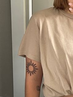 a woman with a sun tattoo on her left arm holding a donut in front of her face