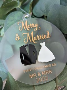 a glass ornament with the words merry and married next to a wedding dress