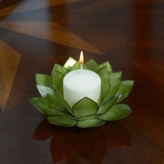 a lit candle sitting on top of a leafy flower shaped bowl with leaves around it