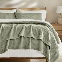 the bed is made with green linens and white pillow cases, along with two nightstands