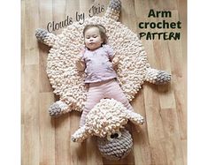 a baby laying on the floor next to a stuffed animal that looks like a sheep